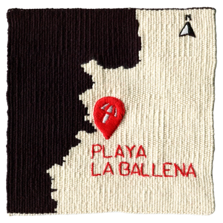Imagen de un tapiz tejido a telar que reproduce un mapa de la costa chilena. El fondo está tejido con hilo negro y el territorio en color crudo. Se percibe también un pin rojo junto al texto “Playa la Ballena” para mostrar dónde está ubicado este sitio de memoria. 